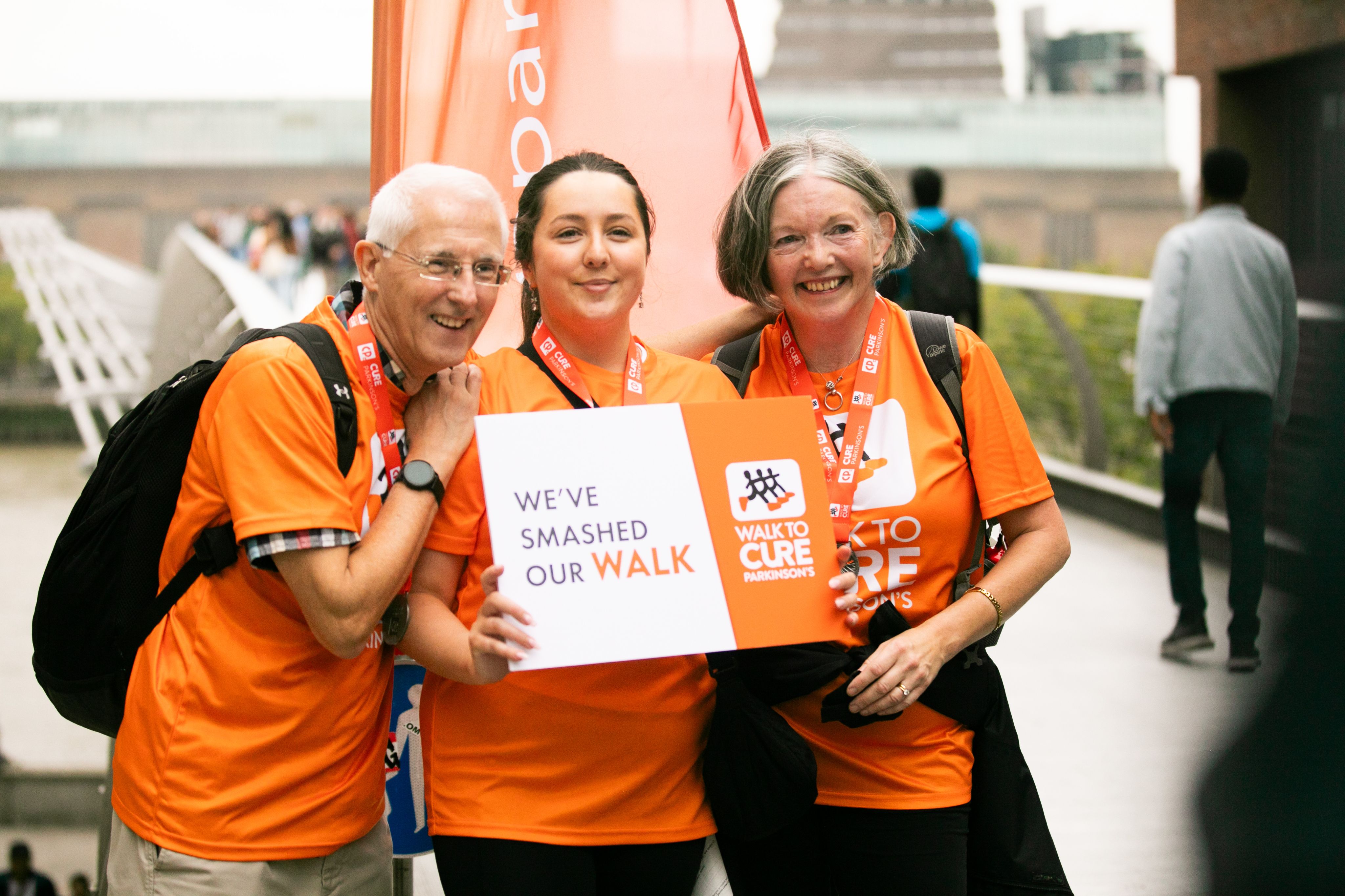 Three fundraisers holding a sign saying "We've smashed our walk"
