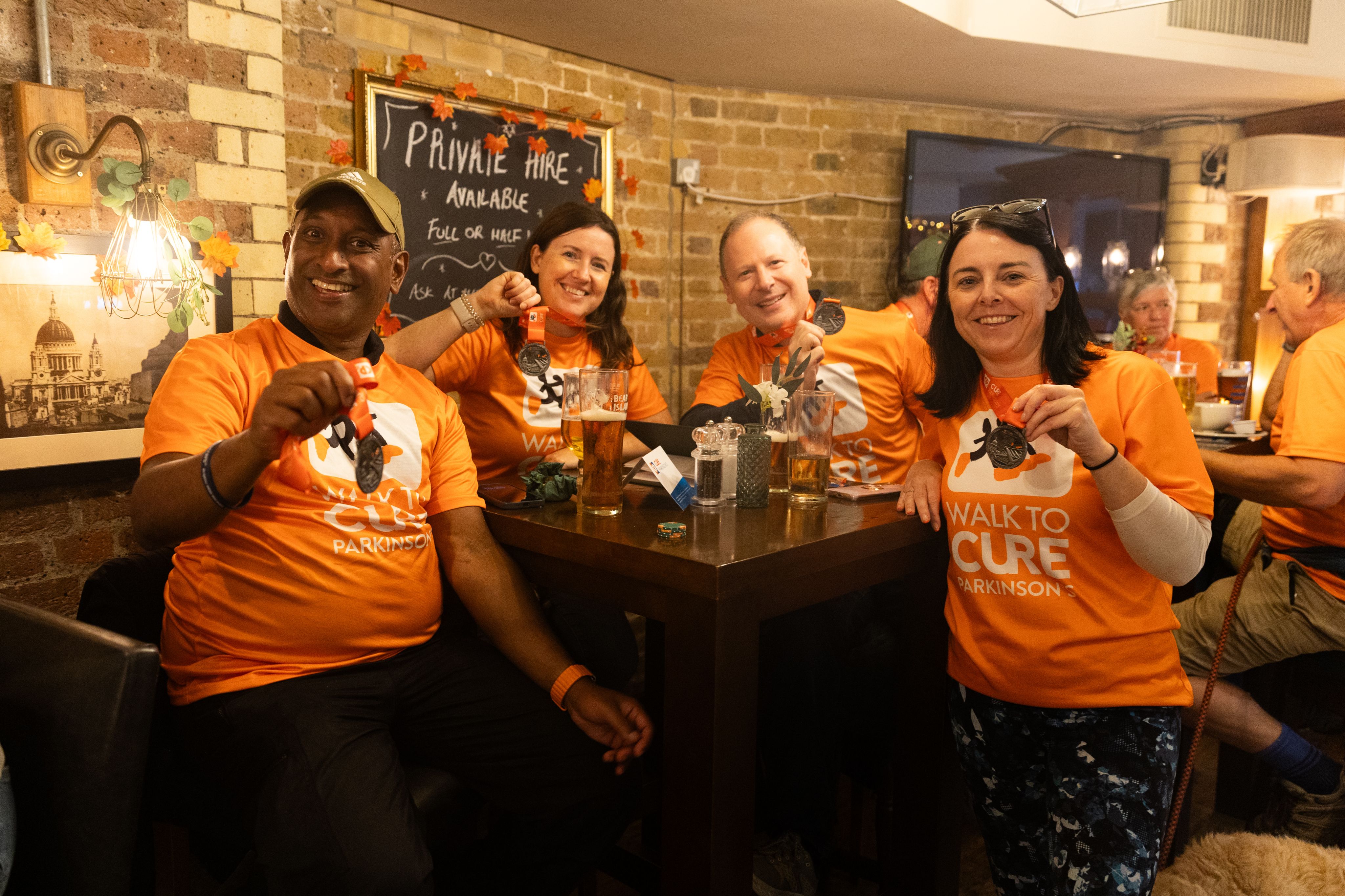 A group of fundraisers show their Walk to Cure Parkinson's medals in a pub.