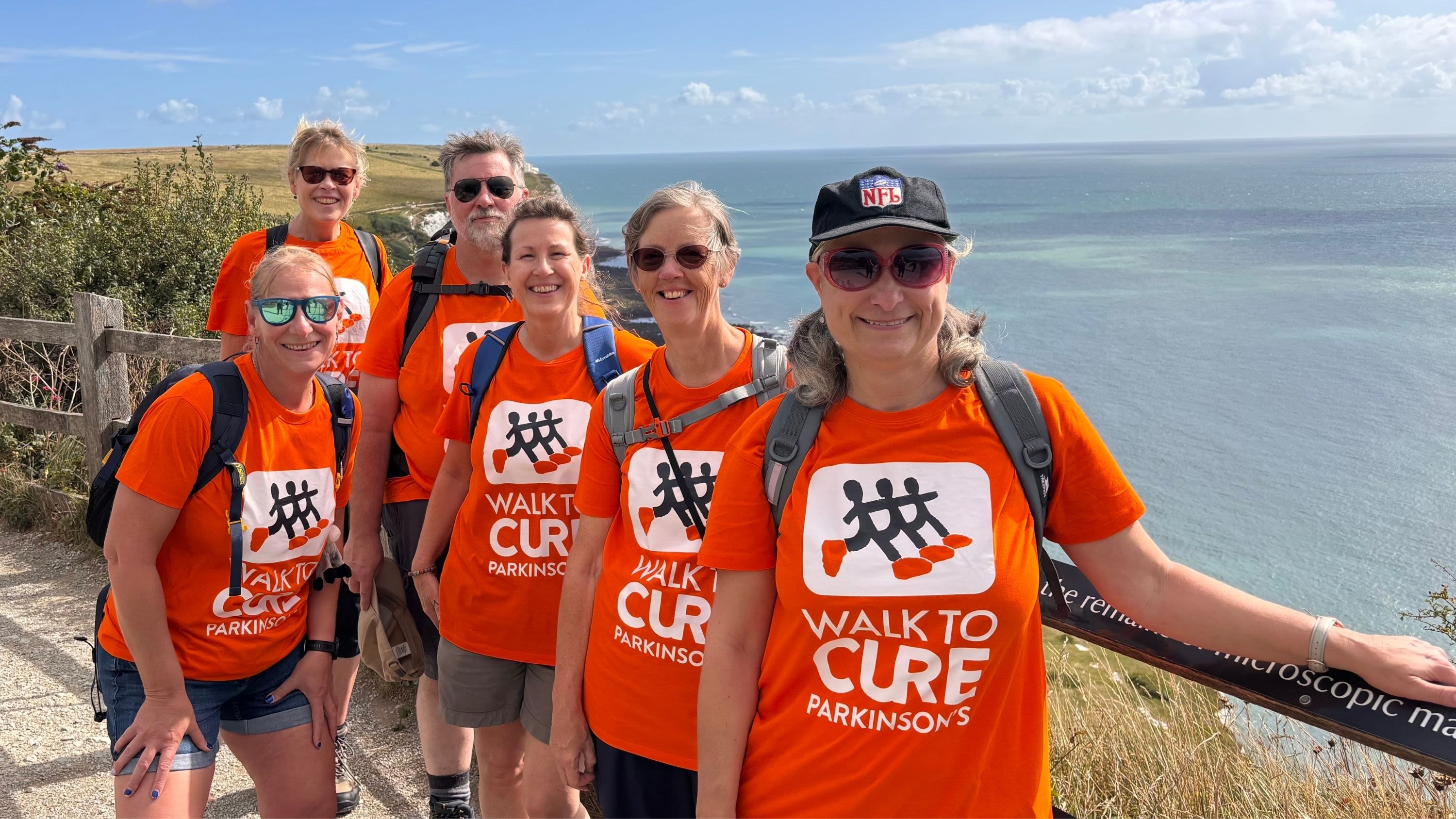 A group of fundraisers in Walk to Cure Parkinson's t-shirts by the coast.